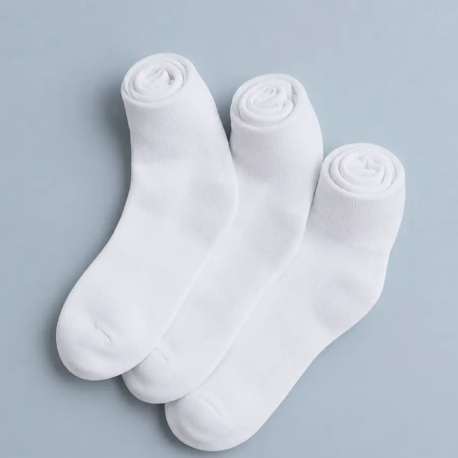 Tres pares de calcetines blancos de algodón enrollados sobre fondo gris azulado