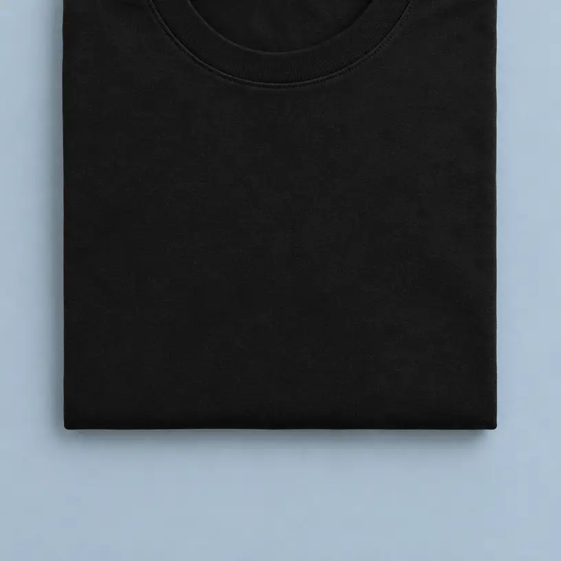 Camiseta negra de cuello redondo doblada sobre fondo gris azulado, vista cenital